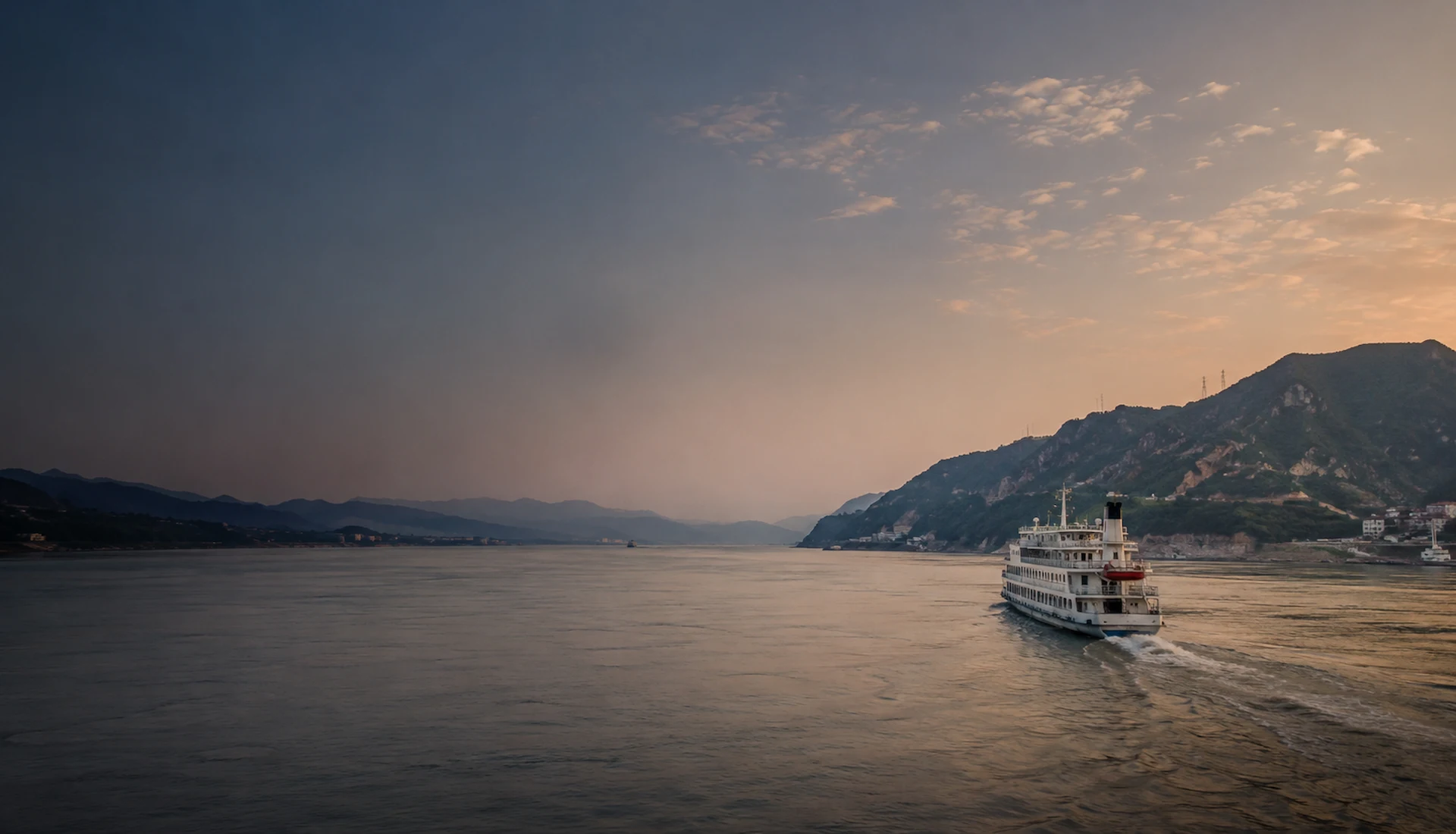 A small vessel moving across the Yangtze toward distant riverbanks